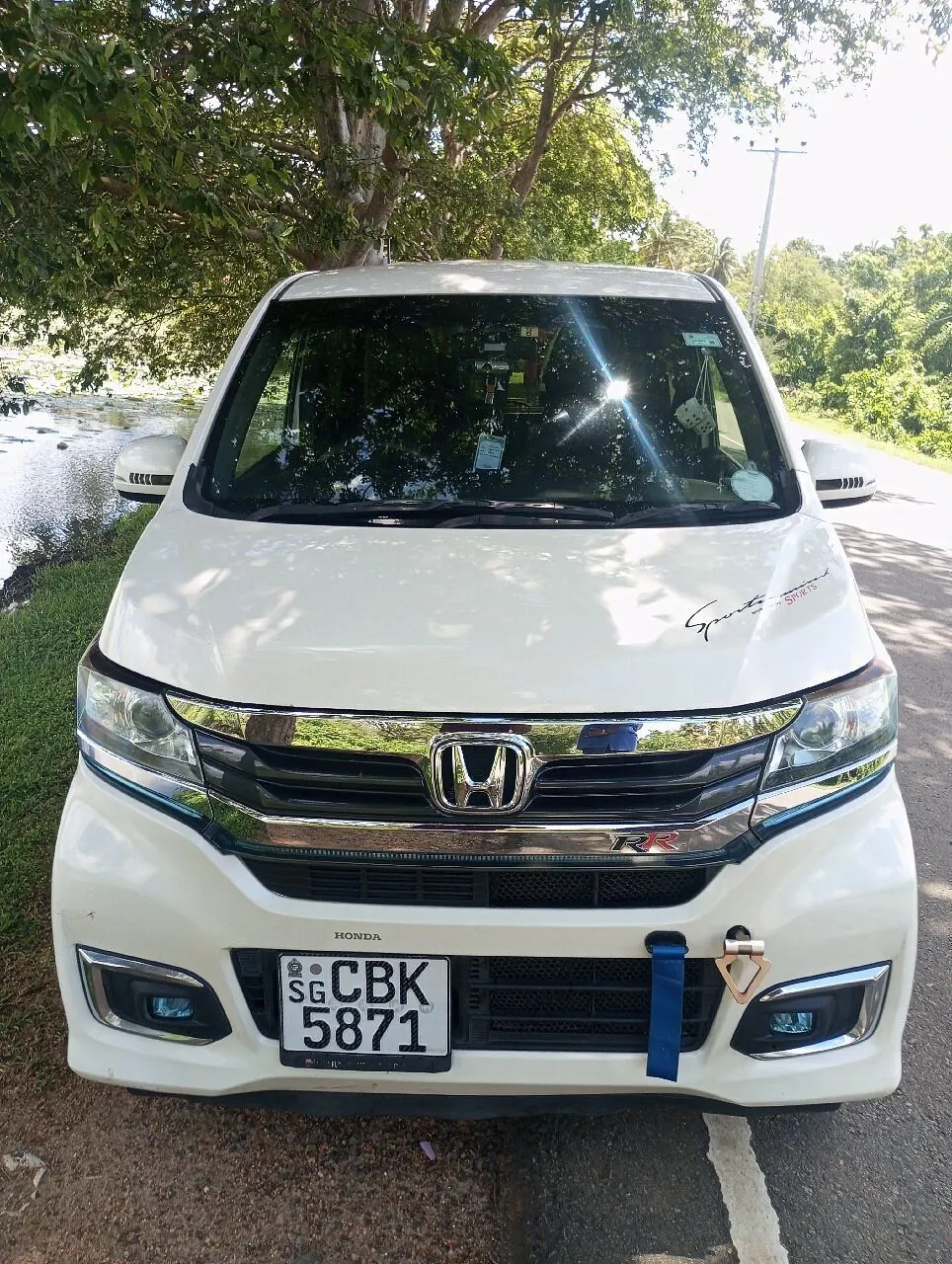Dinu's white Honda parked on a quiet road under trees