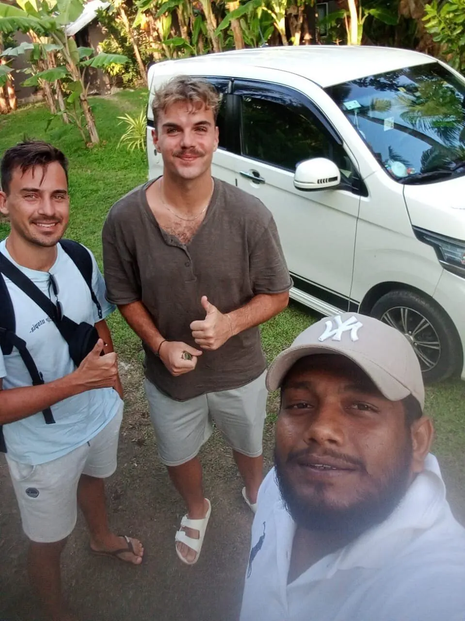 Dinu taking a photo with two guests next to his white car