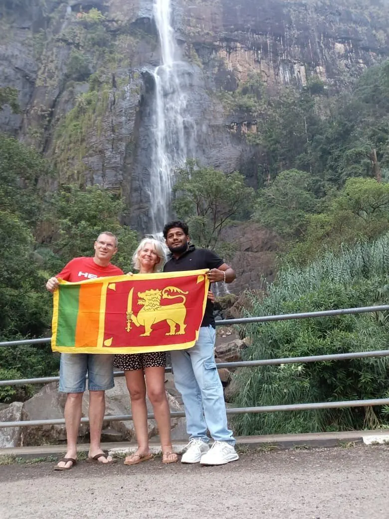 Guests with a Sri Lankan flag in front of a waterfall