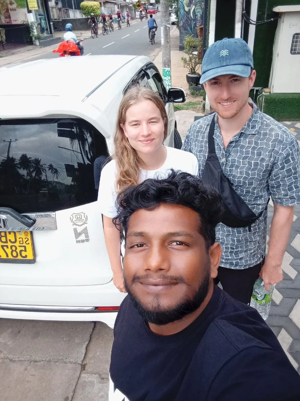 Dinu with two guests next to his car on arrival